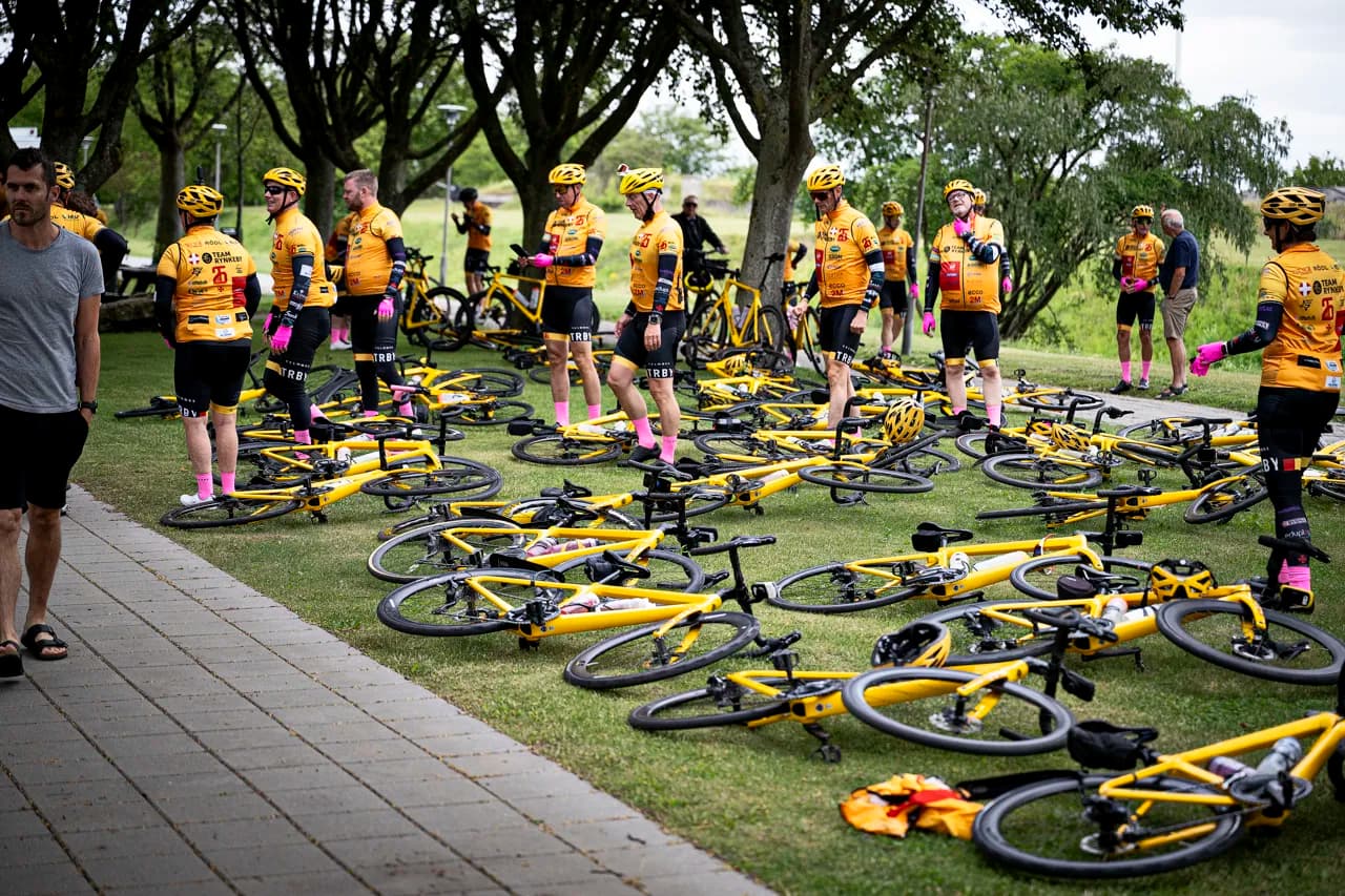 Team Rynkeby riders taking a break next to their yellow bikes on the grass