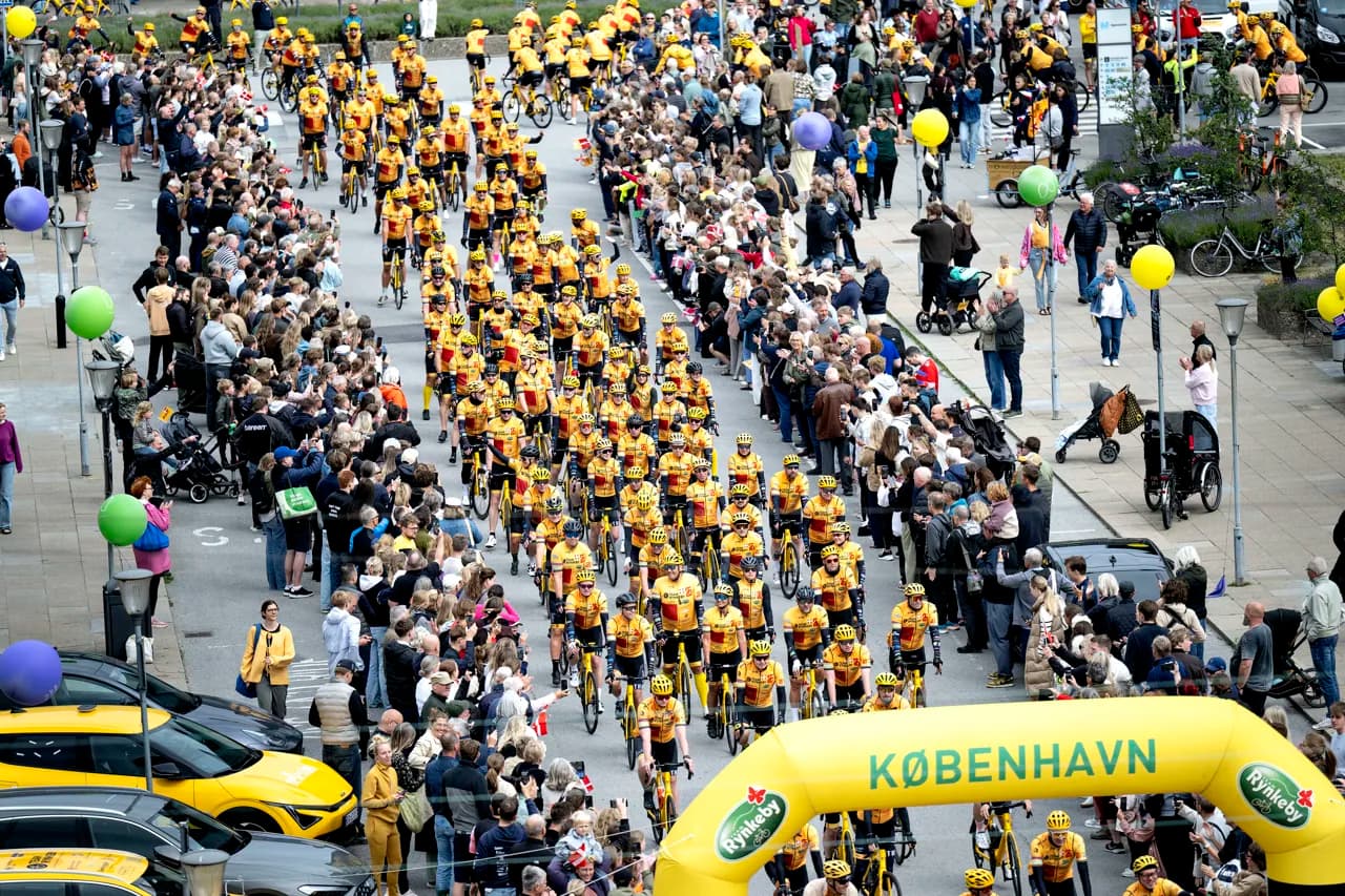 Hundreds of Team Rynkeby riders rolling out under the København start arch, lined by crowds