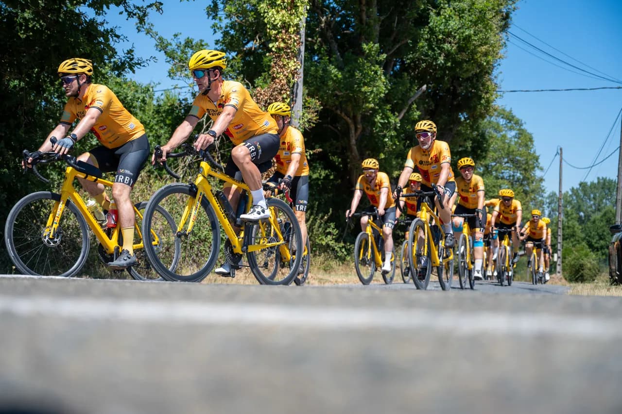 Team Rynkeby riders in yellow jerseys on a sunny country road
